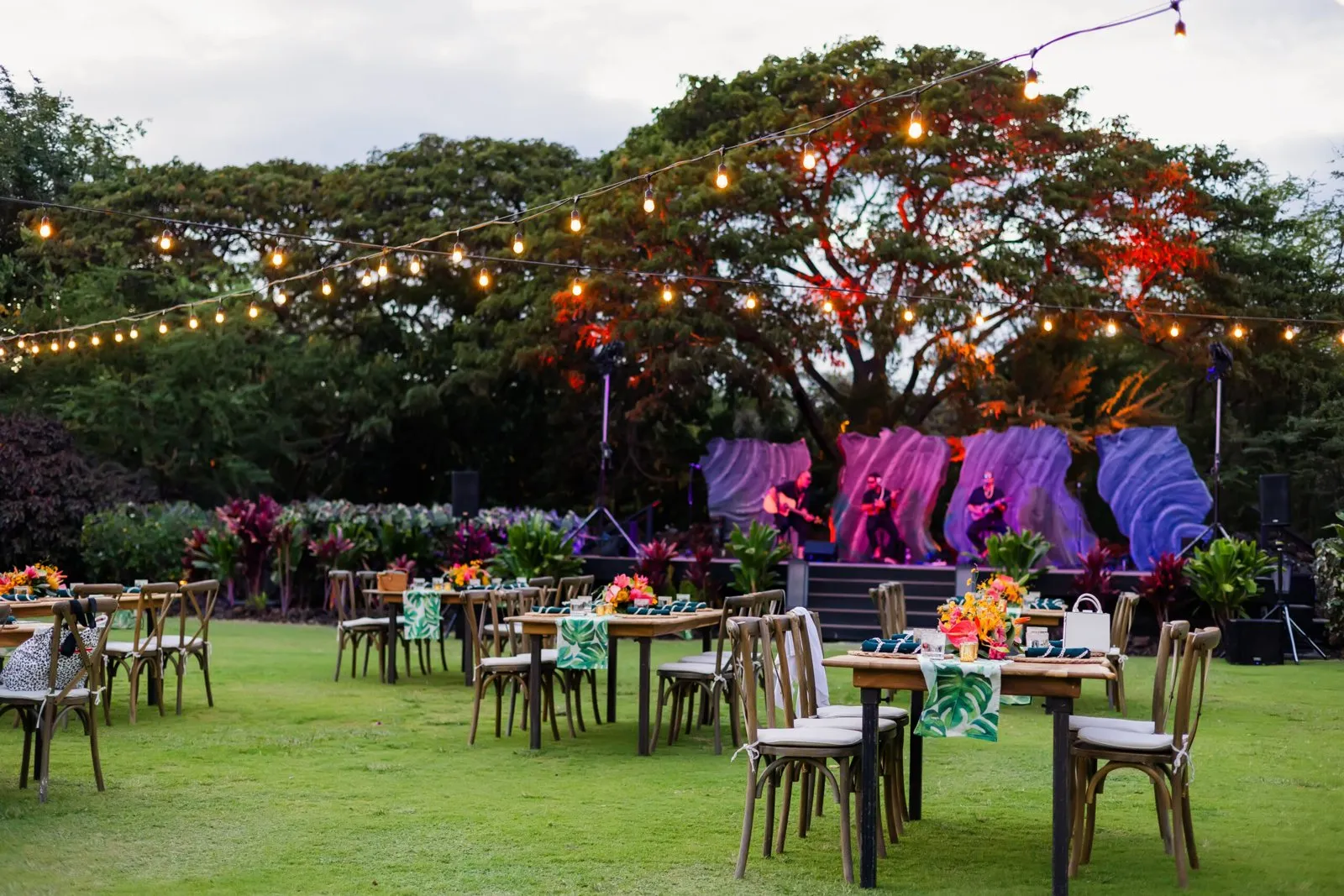 Outdoor dinner tables set on a tropical garden lawn for a corporate group event