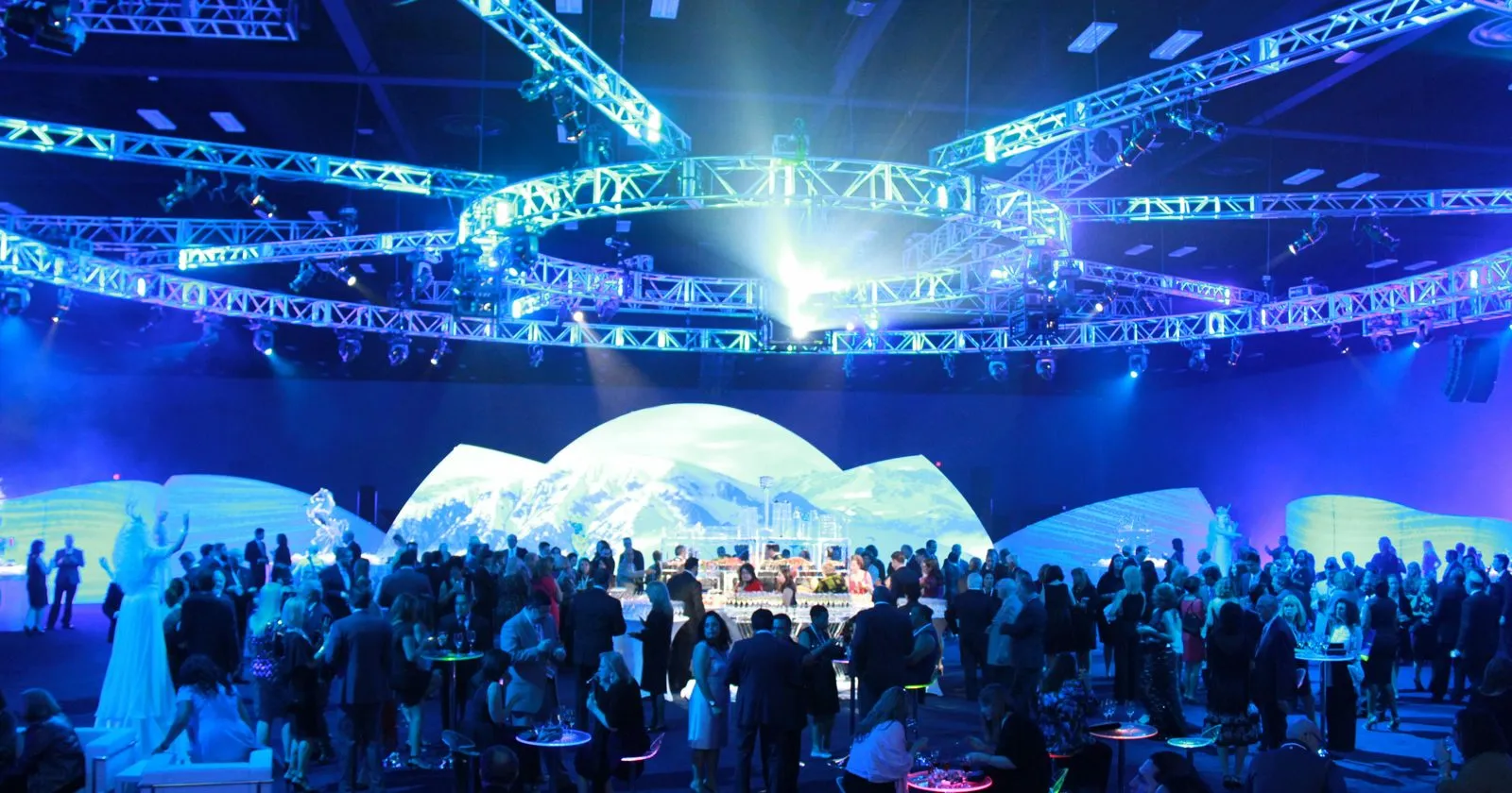 Event hall with overhead truss, a lit stage and a crowd below