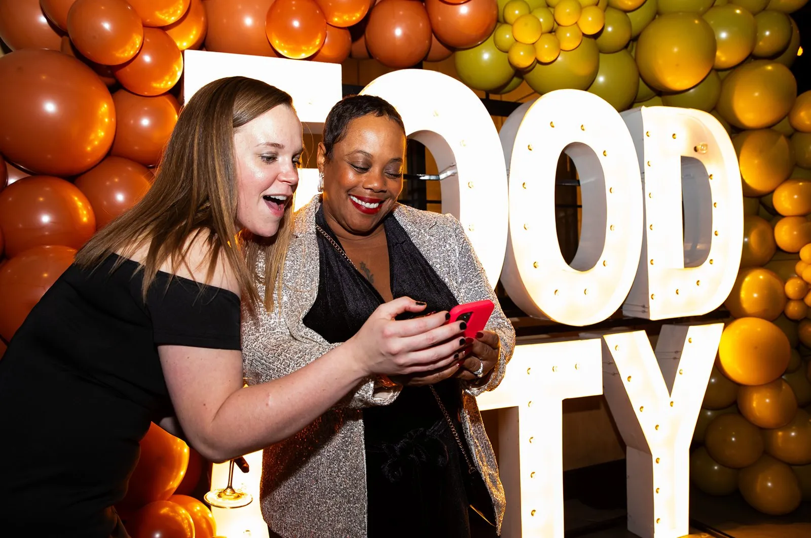 Two guests looking at a phone beside large orange FOOD CITY letters