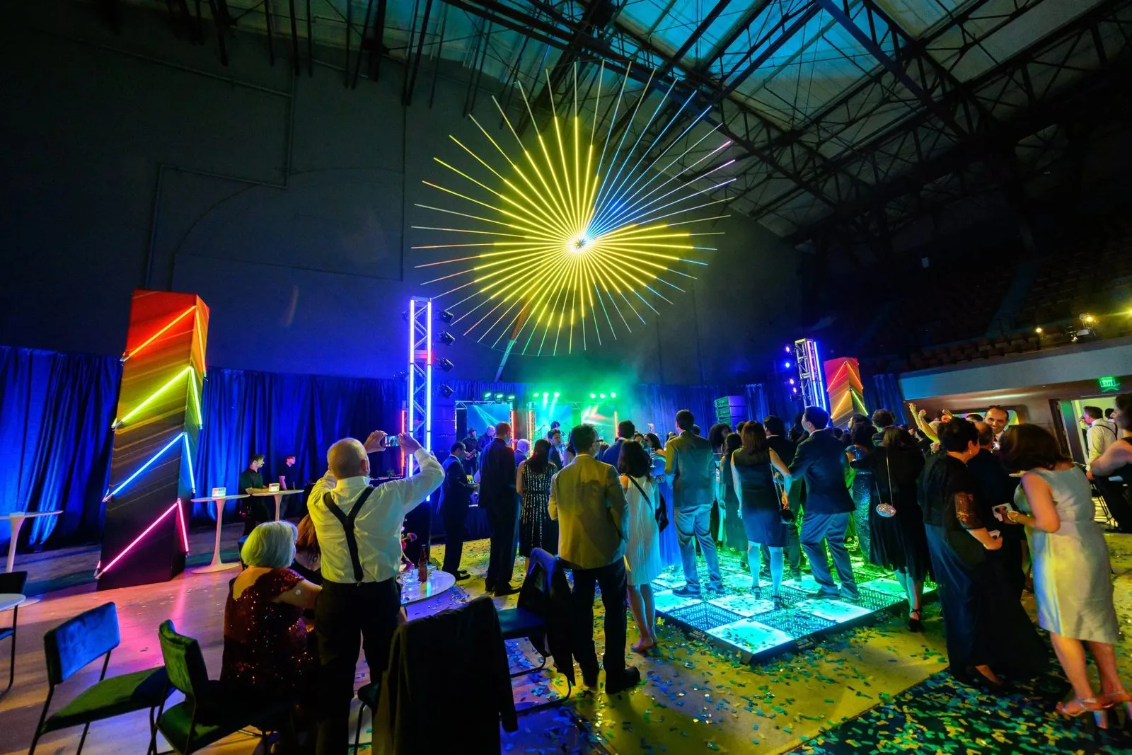 Guests on an illuminated dance floor with stage lighting in an industrial event venue
