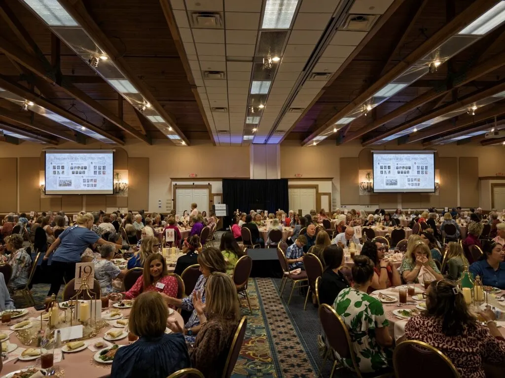 Luncheon in a banquet hall with presentation screens on both sides of the room