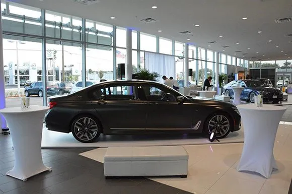 Car showroom set with a vehicle on display and cocktail tables