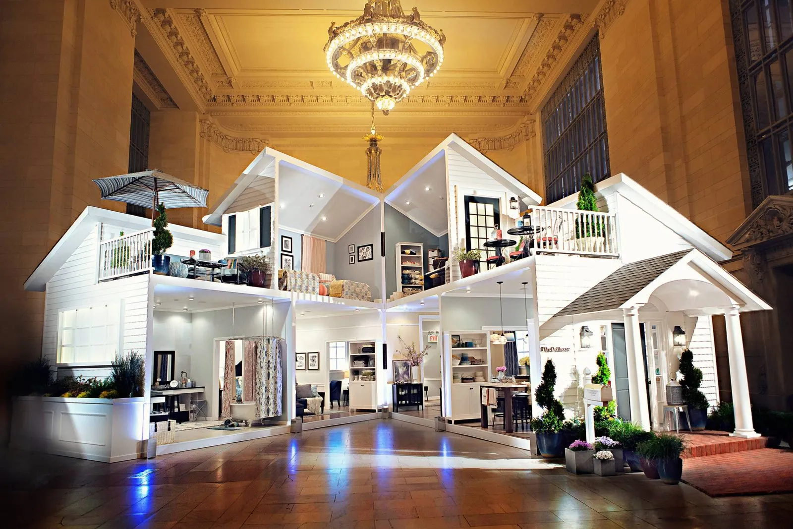 Walk-in house installation staged inside a grand hall with a chandelier