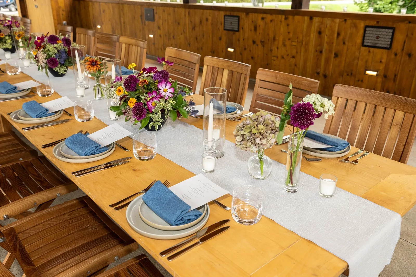Table settings with blue napkins and floral centerpieces inside the covered bridge