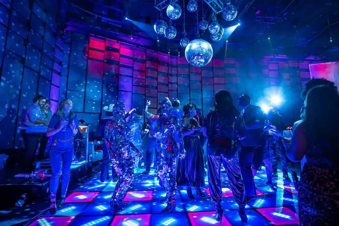 Guests on a lit dance floor under a disco ball