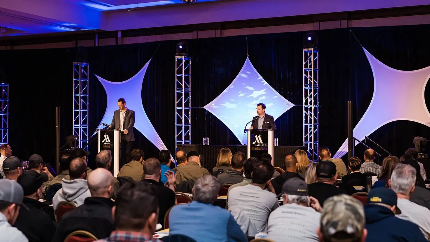 Audience watching a presentation on a lit stage at a corporate meeting