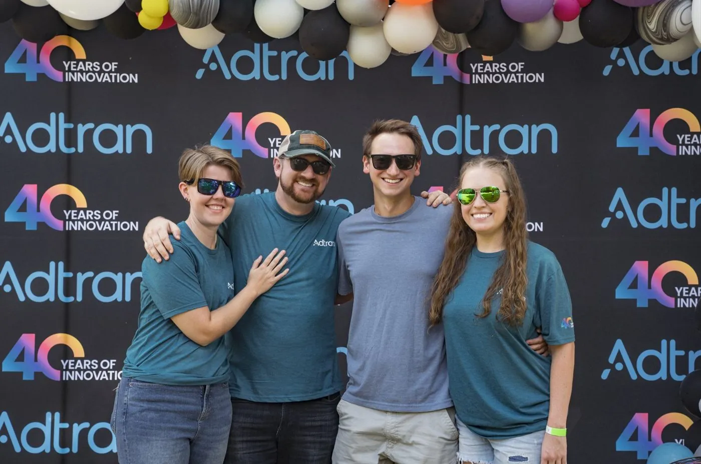 Employees posing in front of a company anniversary photo backdrop at an event