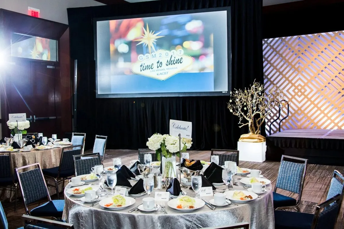 Banquet tables set in front of a stage with a projection screen