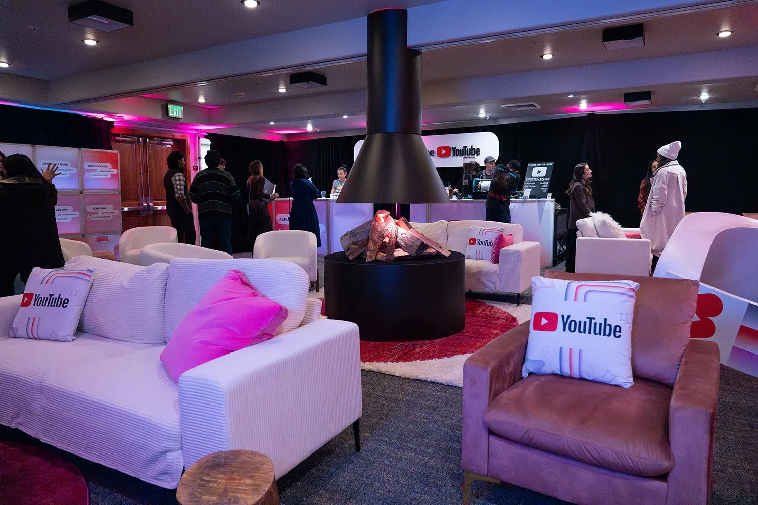 YouTube-branded lounge in Park City with white sofas, pink pillows and a hanging fireplace