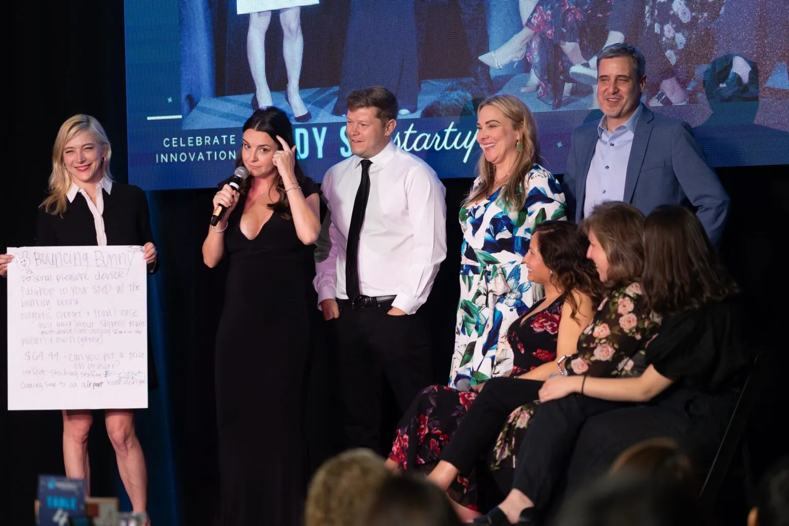 Speakers on a stage with a screen behind them at a startup pitch event