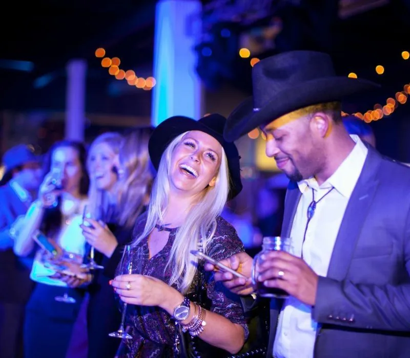 Guests in western hats holding drinks at a themed company party