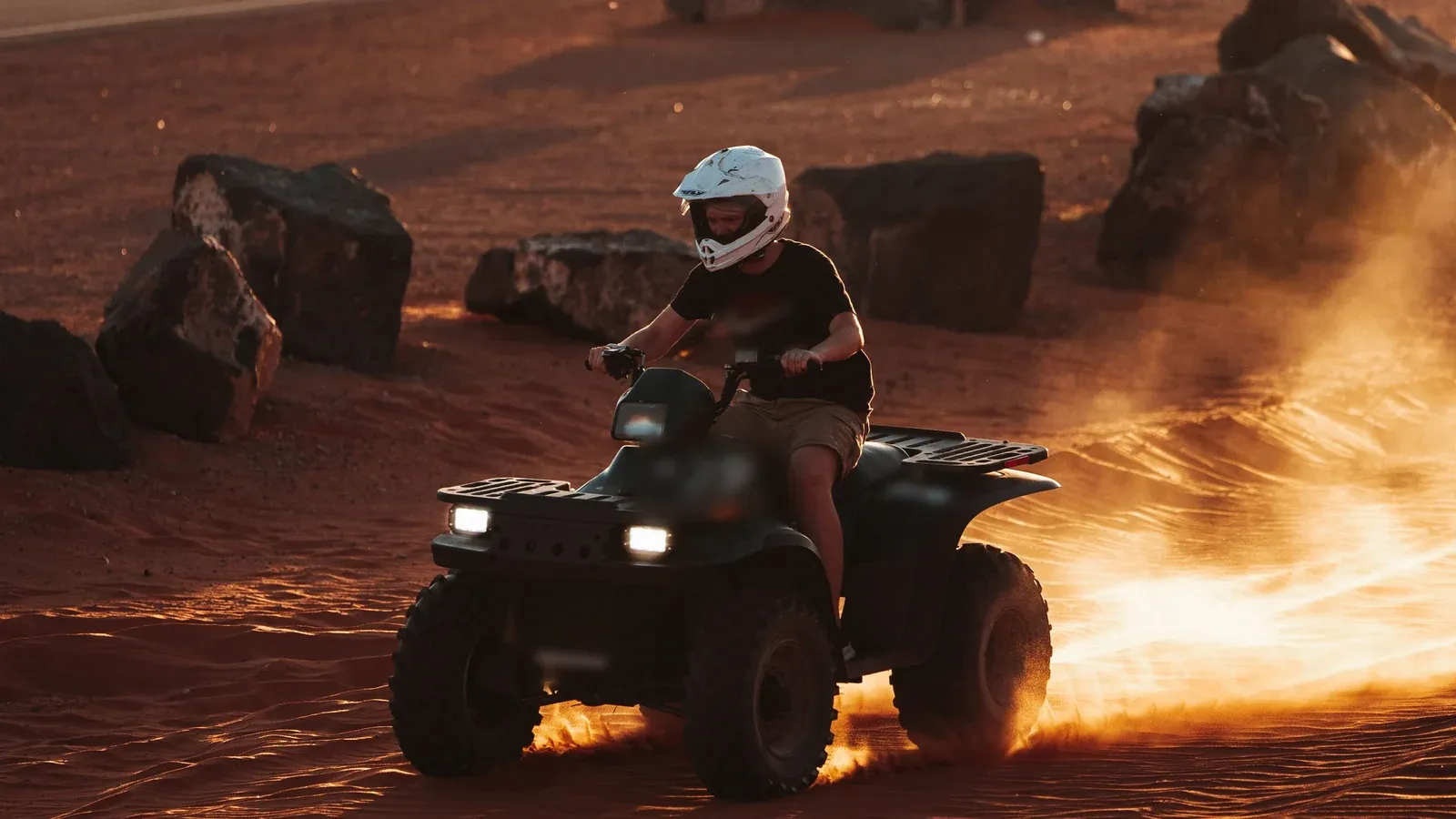 A helmeted rider kicks up golden dust on a desert ATV run at sunset during an incentive trip in Arizona.
