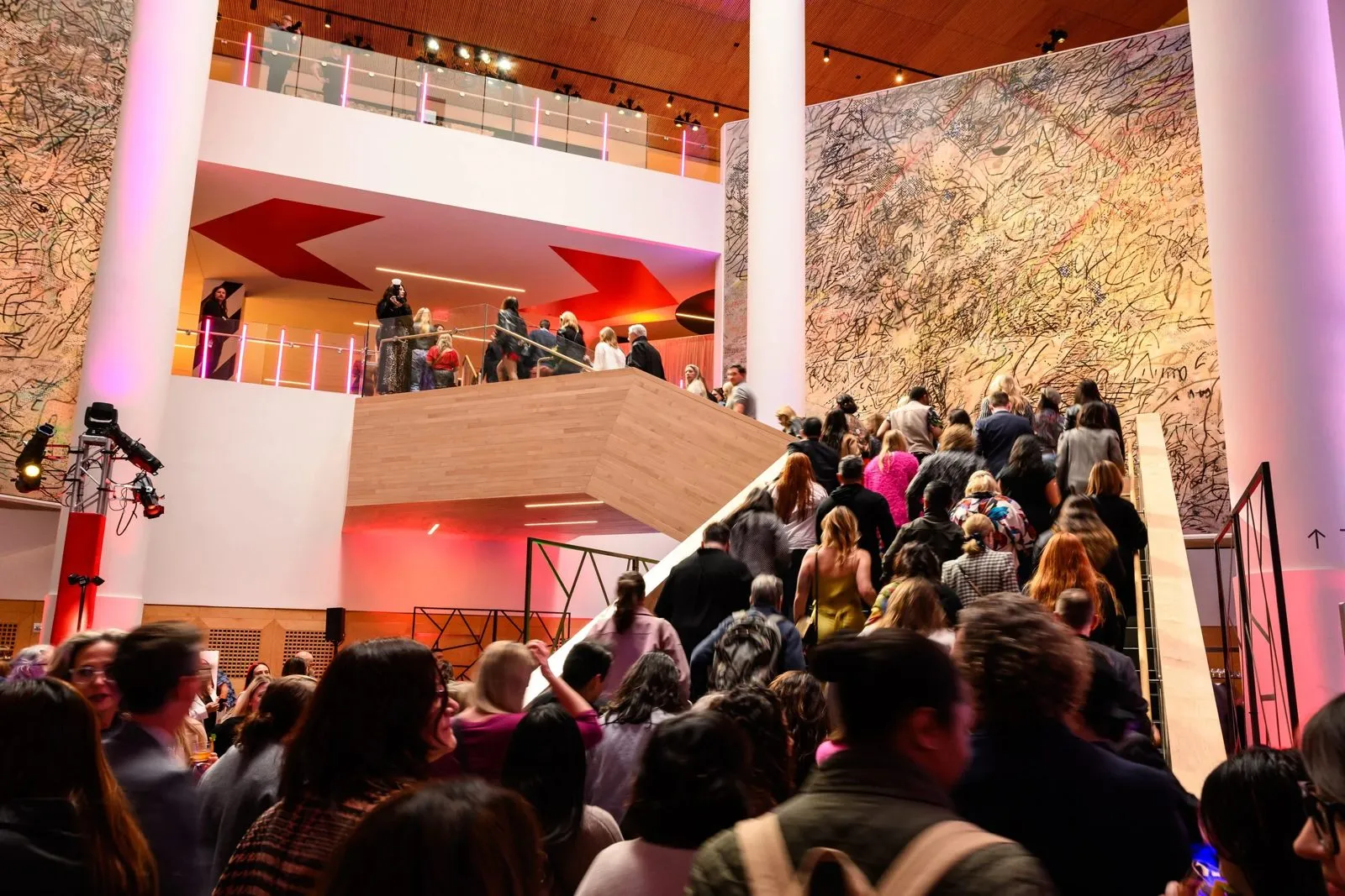 Guests gathered on the floors and stairs of a multi-level museum atrium during a corporate reception