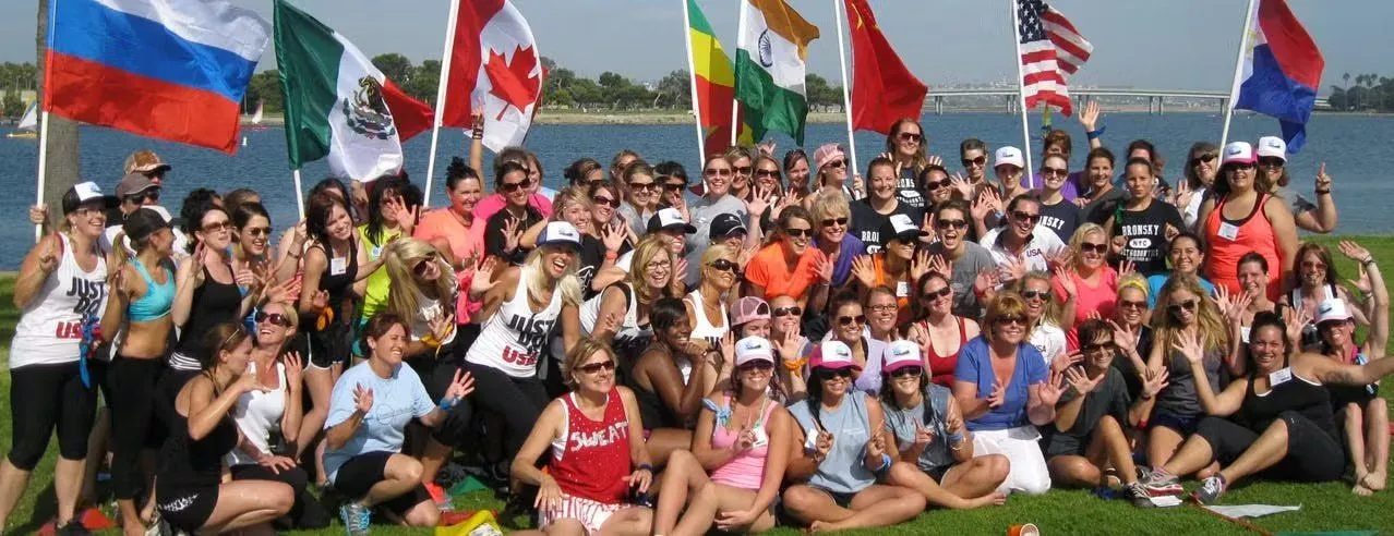 Large group on a lawn by the water with international flags