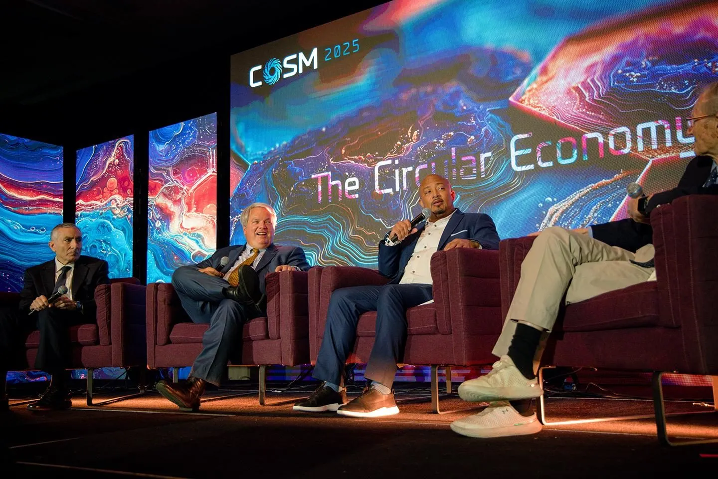 Panel discussion on stage at a technology summit with large video screens