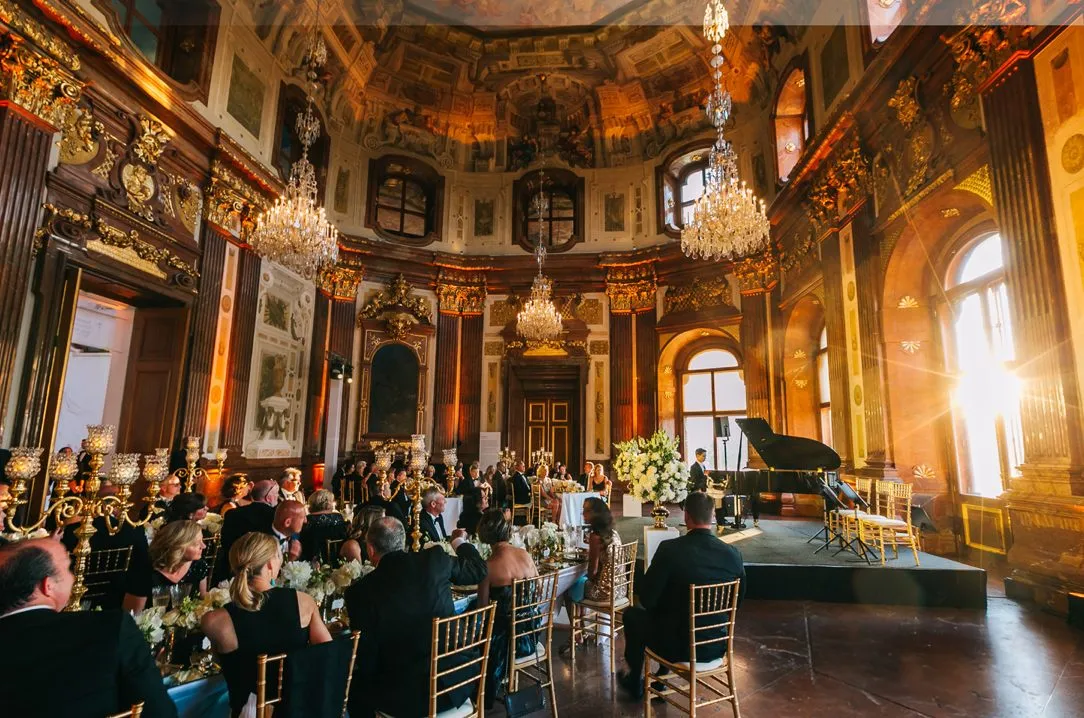 Guests seated at long tables in an ornate gilded hall
