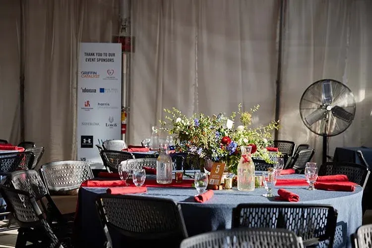 Tented dinner at Utah Olympic Park with a floral centerpiece and red napkins