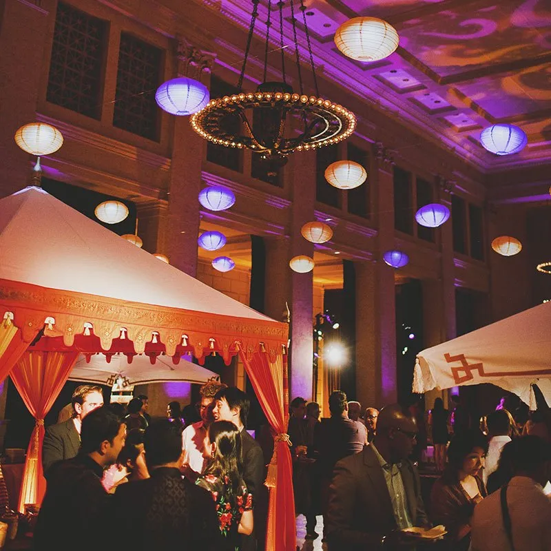 Evening event in a ballroom with lanterns and red tented lounges