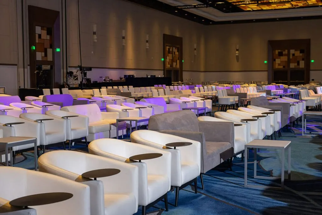 Rows of white lounge seating with purple lighting in a hotel ballroom