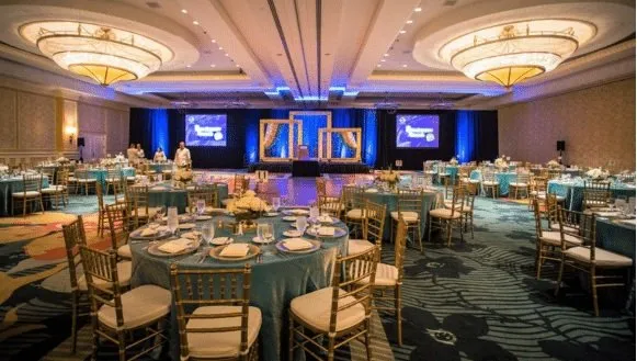 Ballroom general session with round tables and three stage screens