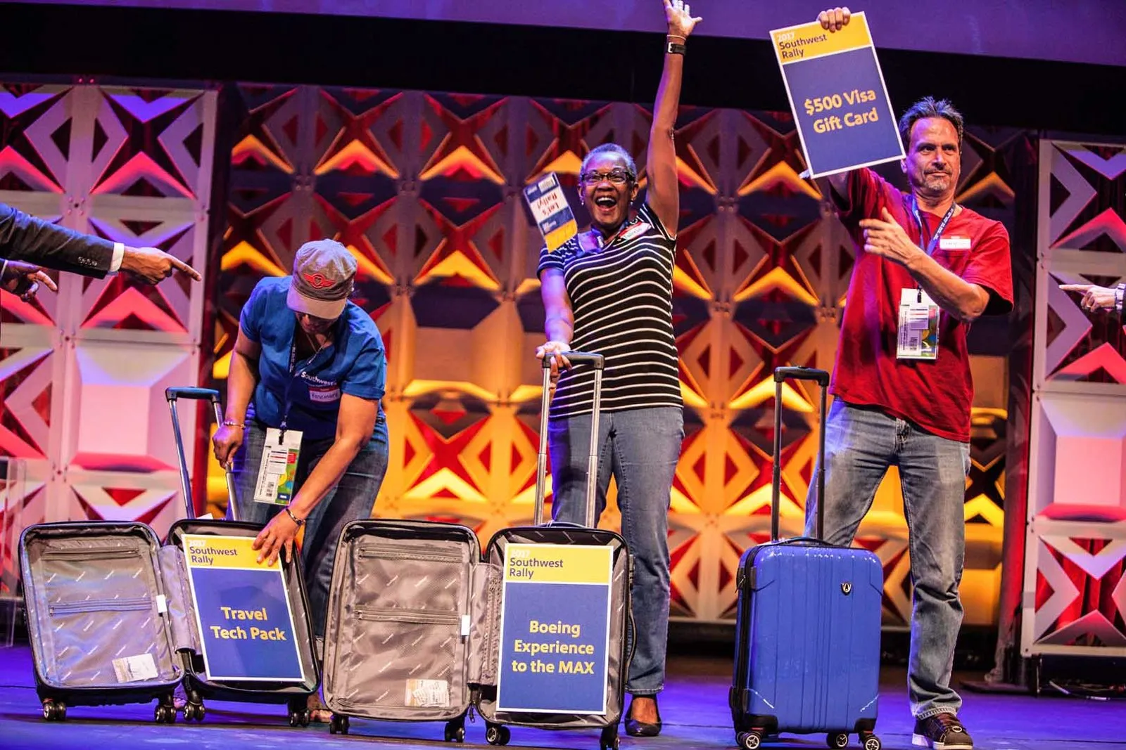 Attendees with suitcases and signs on a lit stage at a Southwest rally