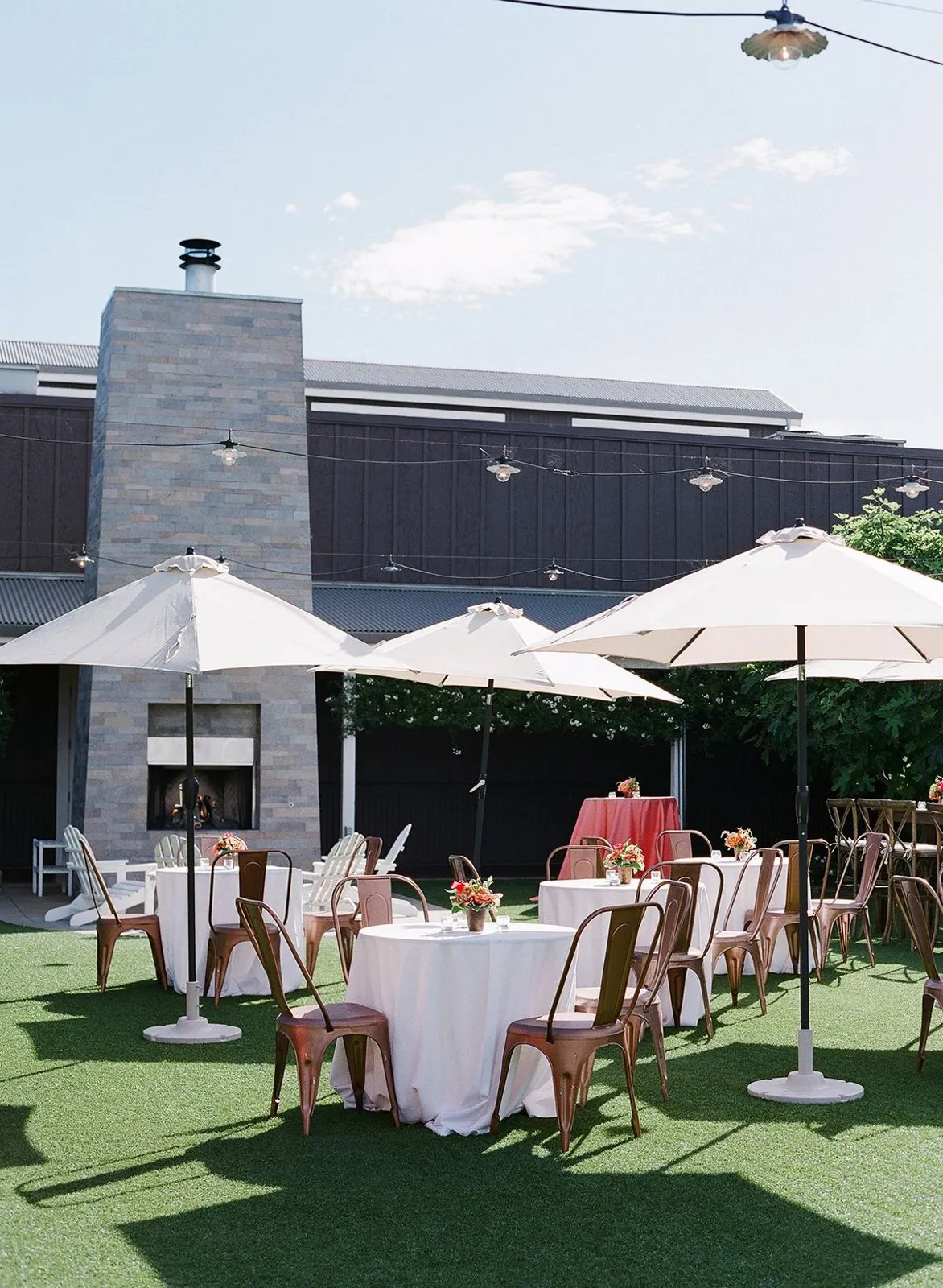 Outdoor patio reception with white umbrellas and cocktail tables