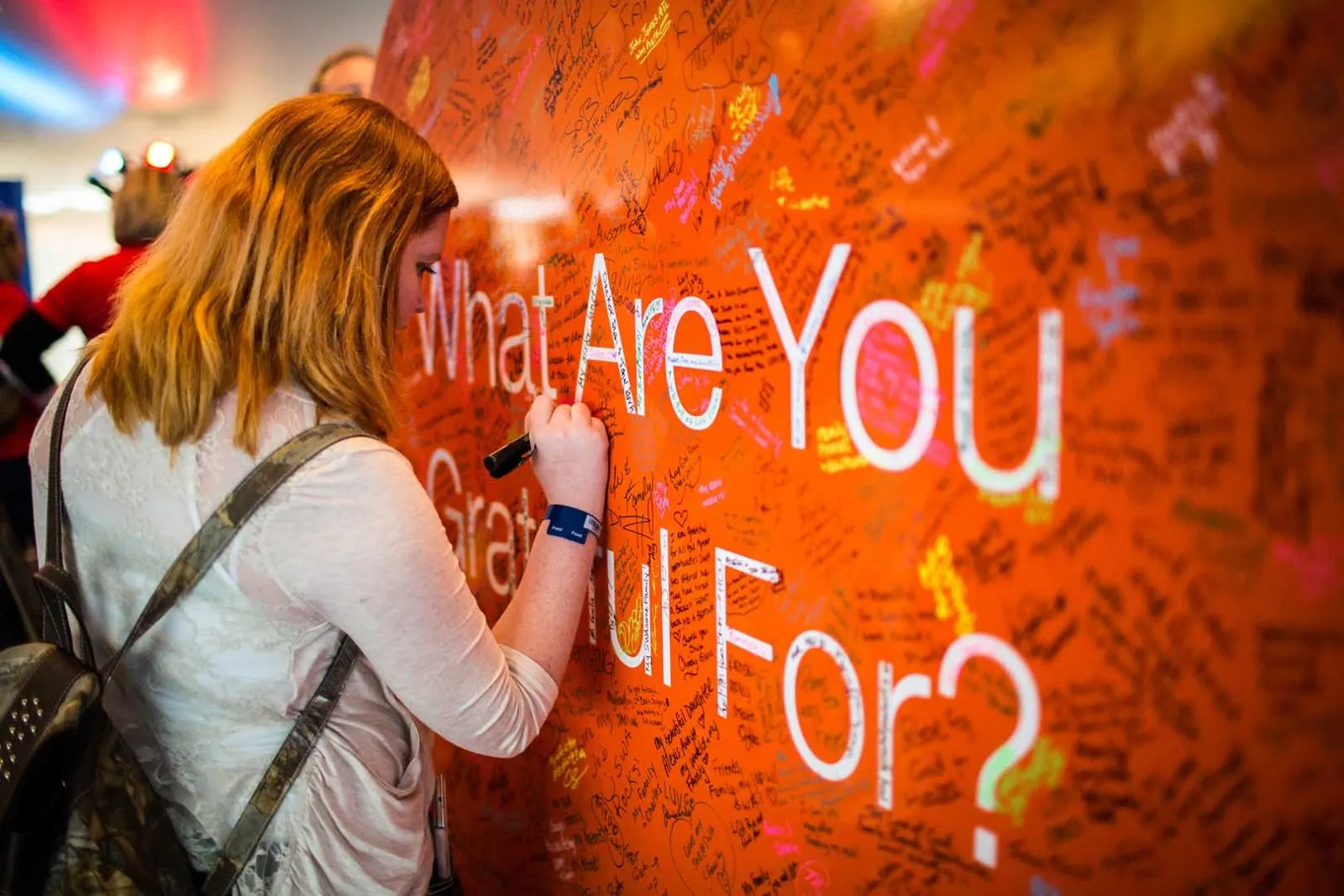 Attendee writing on an orange gratitude wall at a conference