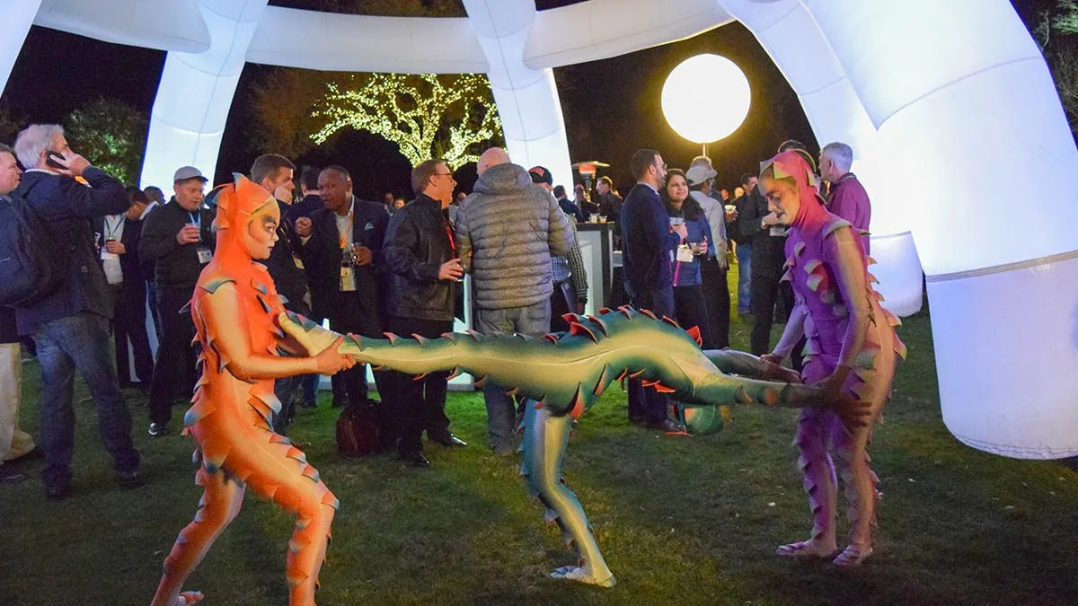 Costumed performers entertaining guests on a lawn near a white tent