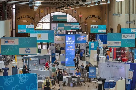 Trade show floor in an arched hall with attendees at branded booths