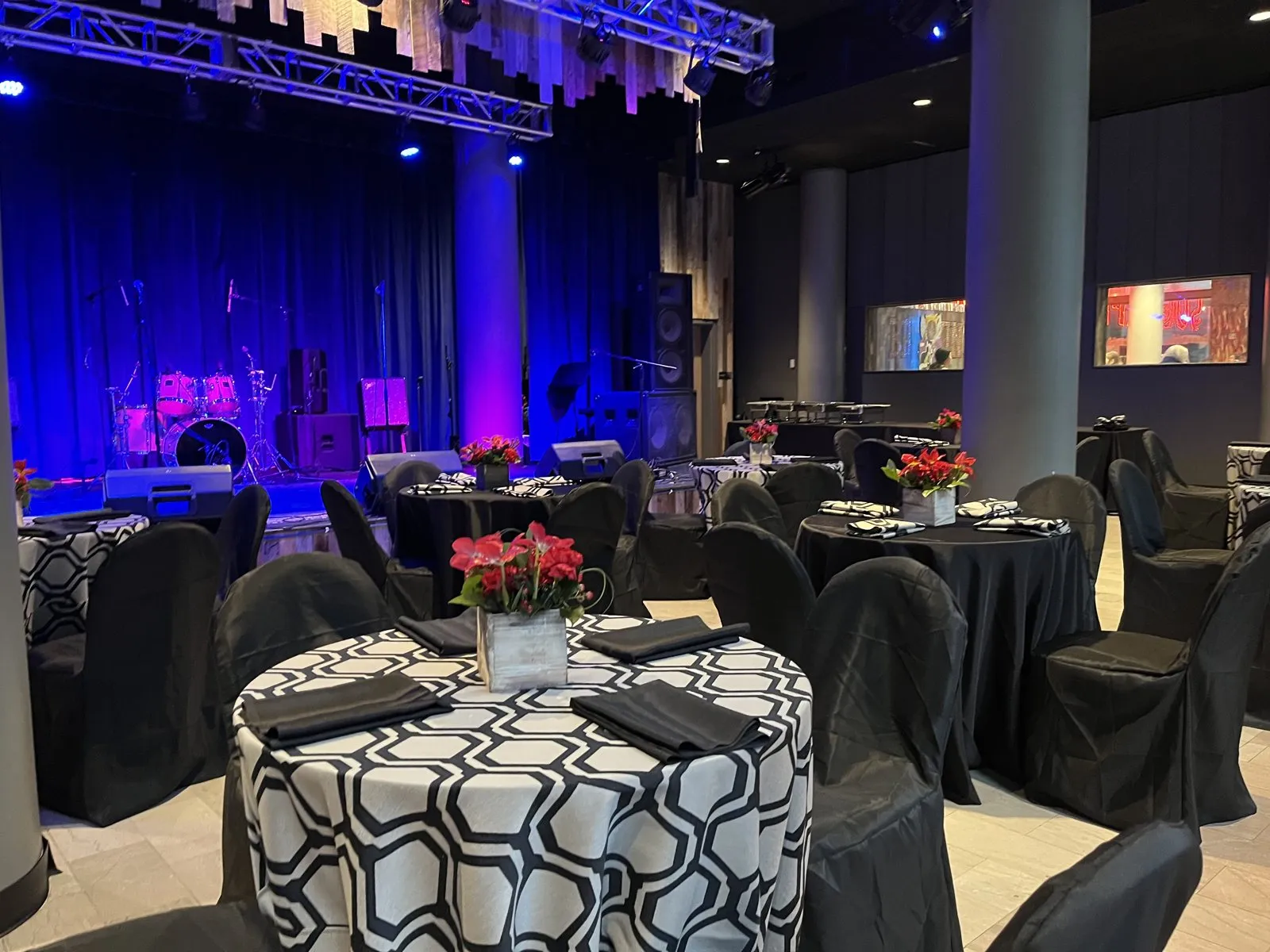 Round tables with patterned linens set before a stage lit in blue and purple