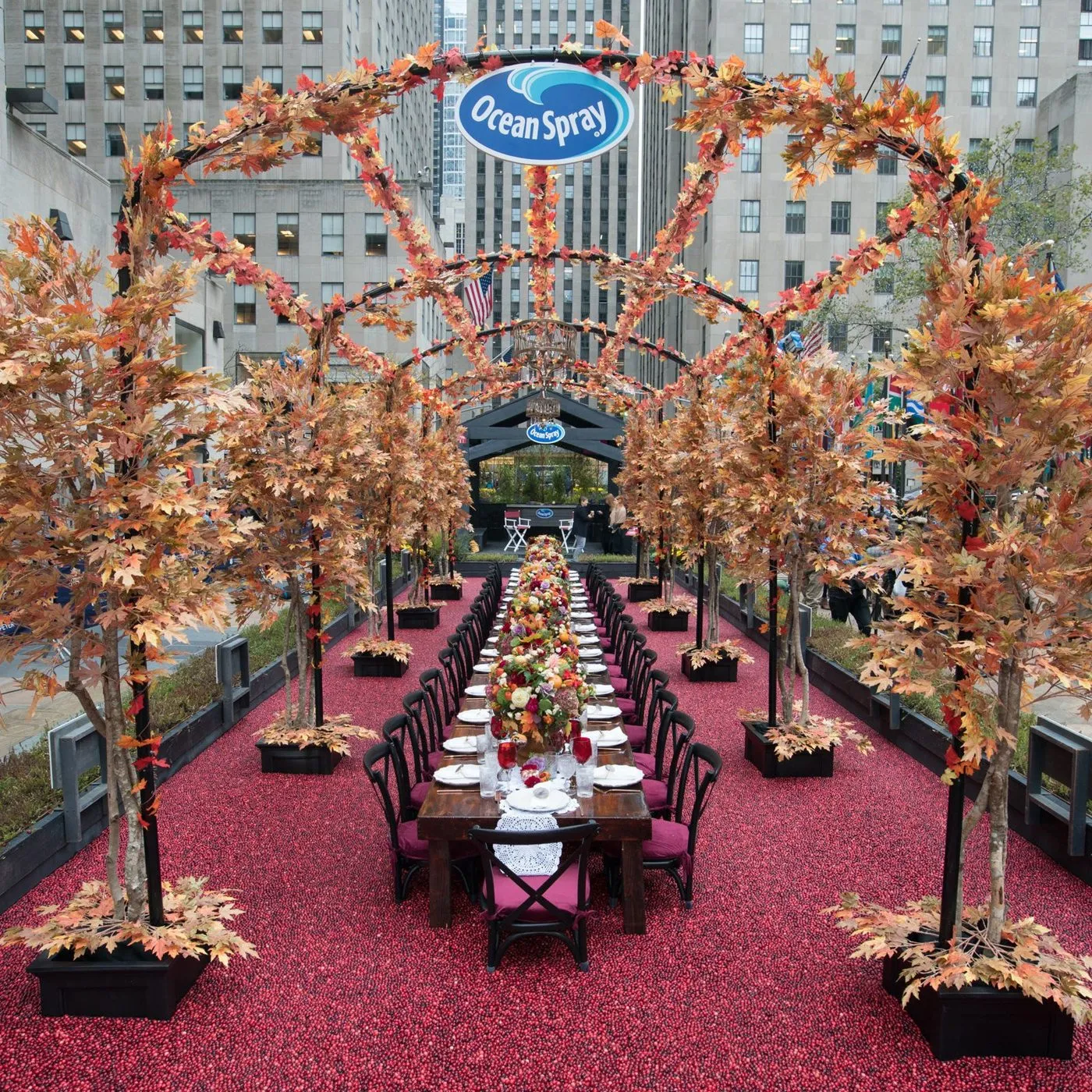 Long dinner table set under branded arches on a plaza