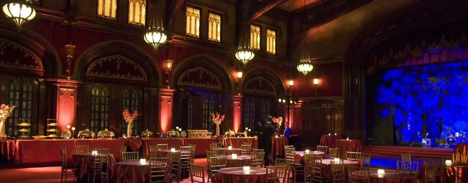 Round dinner tables set in an ornate ballroom with accent lighting