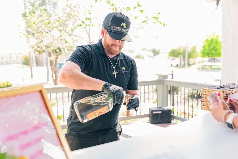 Bartender pouring a drink at an outdoor event bar