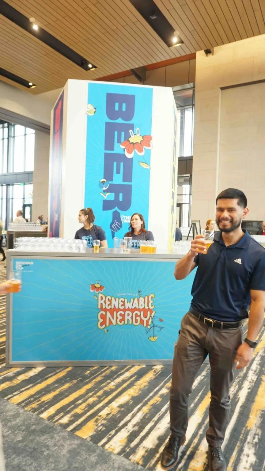 Staff member beside a branded blue display at a corporate brand activation
