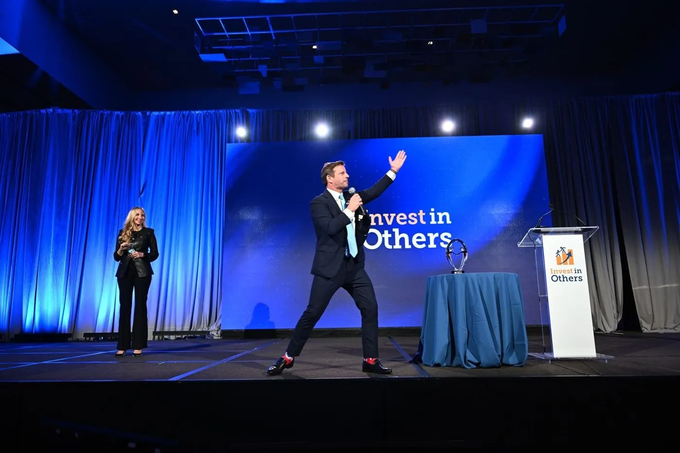 Keynote speaker on stage with blue lighting at a conference