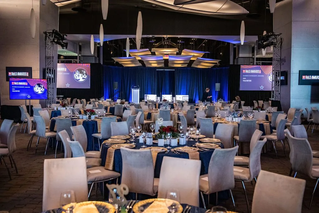 Large ballroom set with round tables and screens for a corporate program