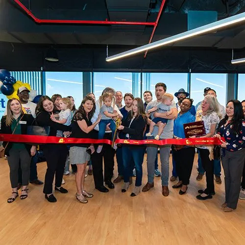 Group gathered behind a ribbon for a grand opening