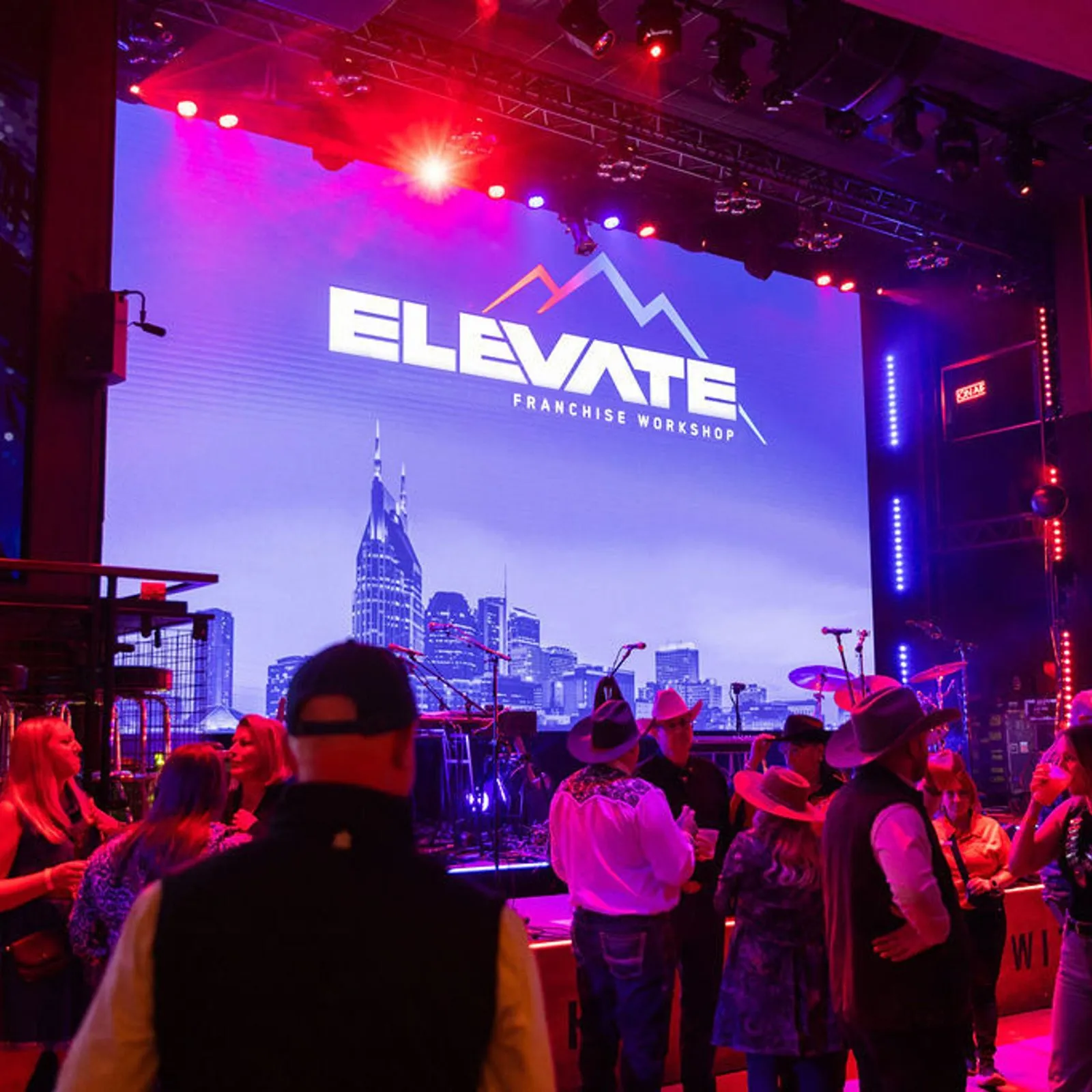 Elevate stage with a lit screen at an evening session