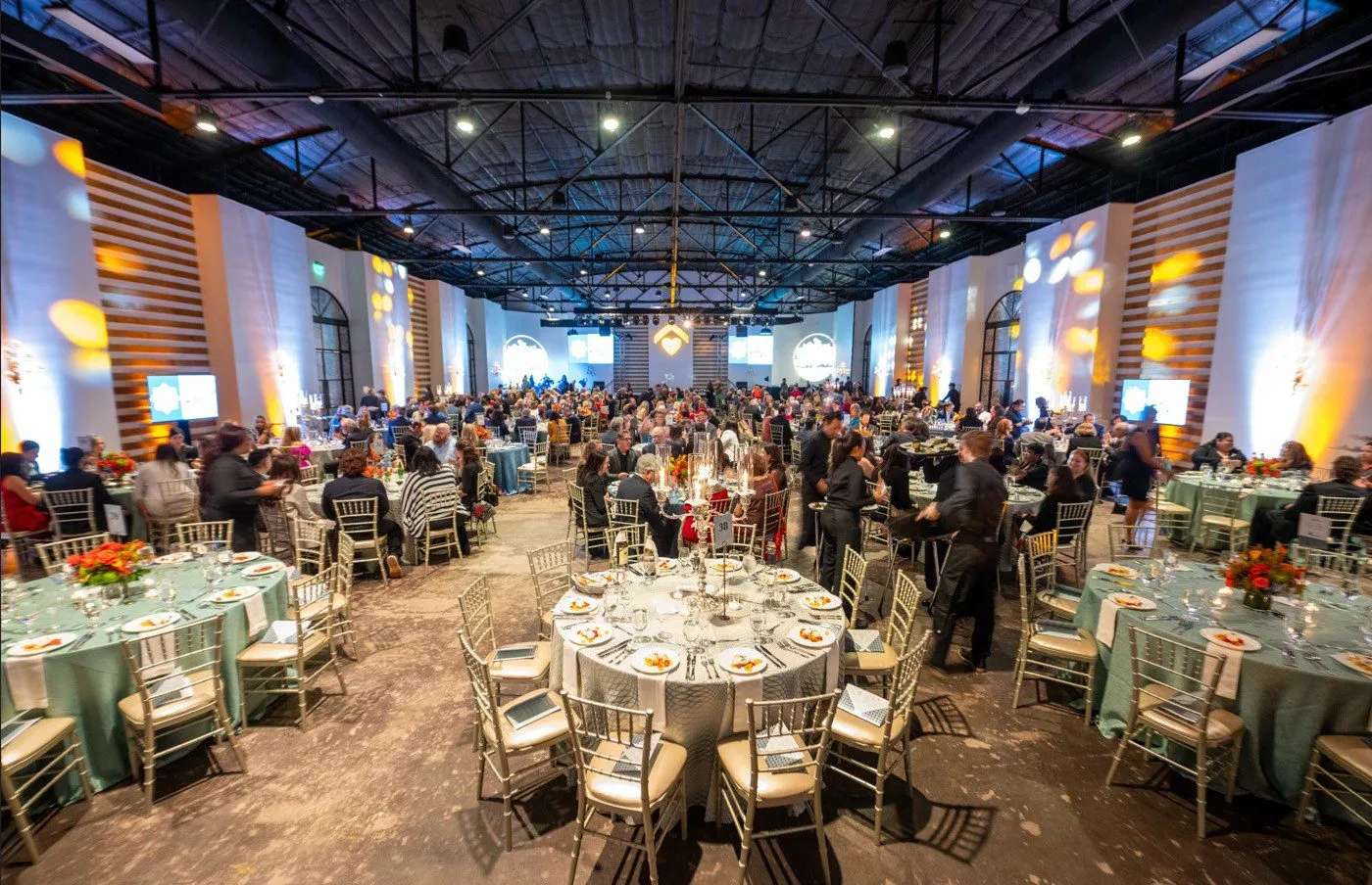 Large round table dinner in a ballroom with a lit ceiling