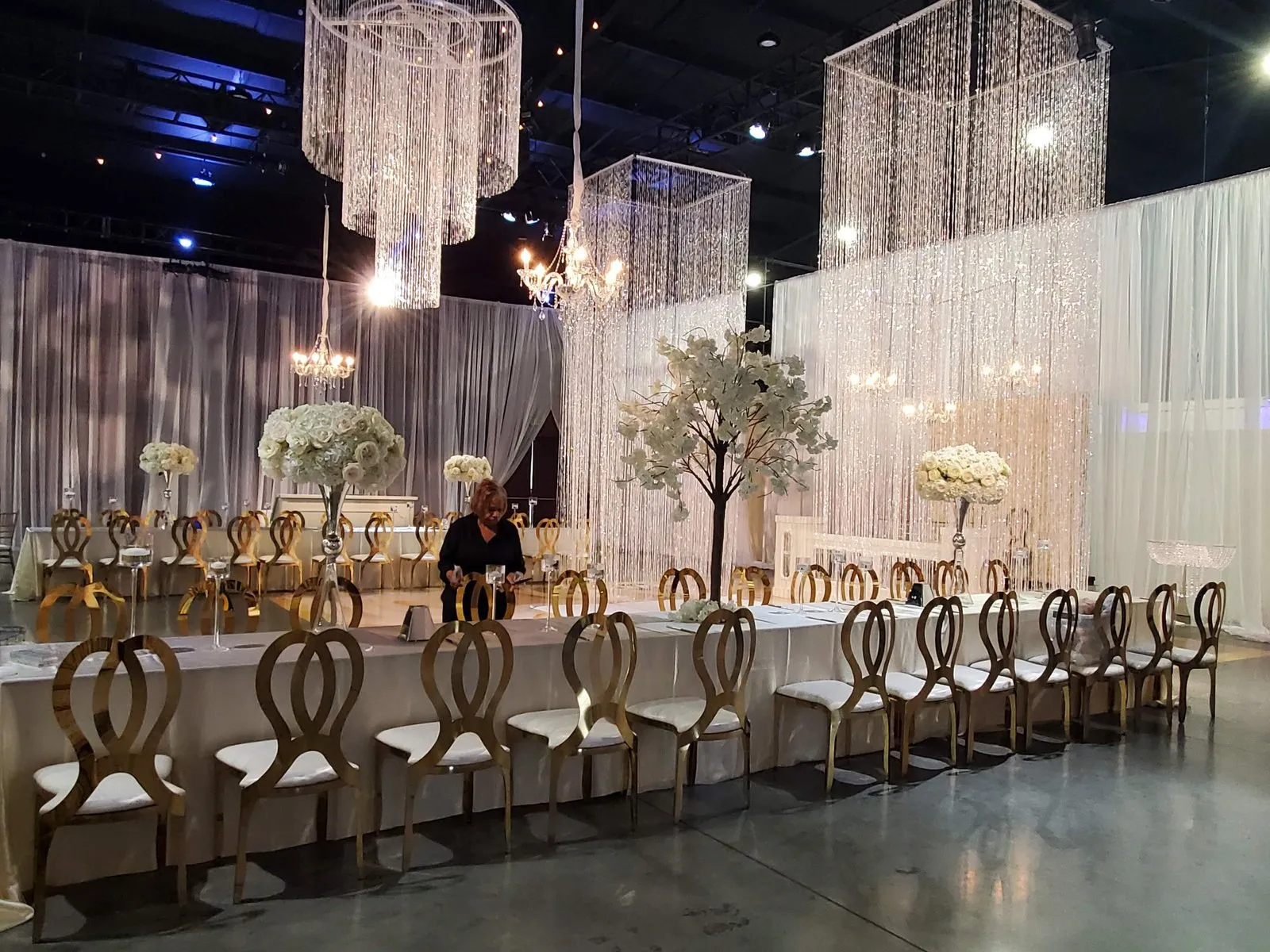 Long banquet table under crystal chandeliers with white draping