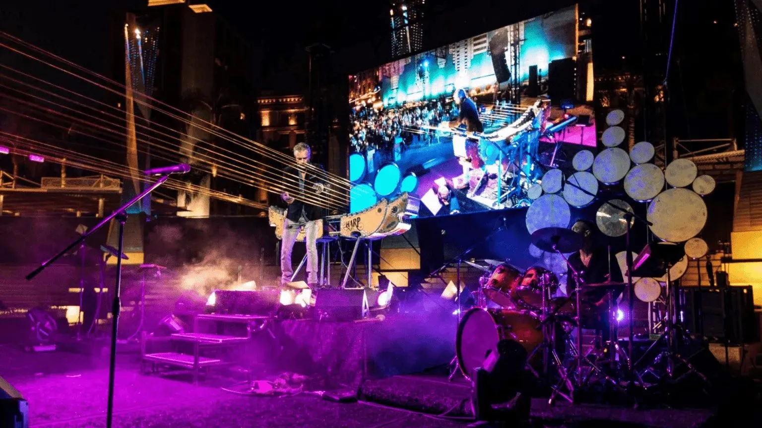 Band playing on a stage with a large video wall at an evening event