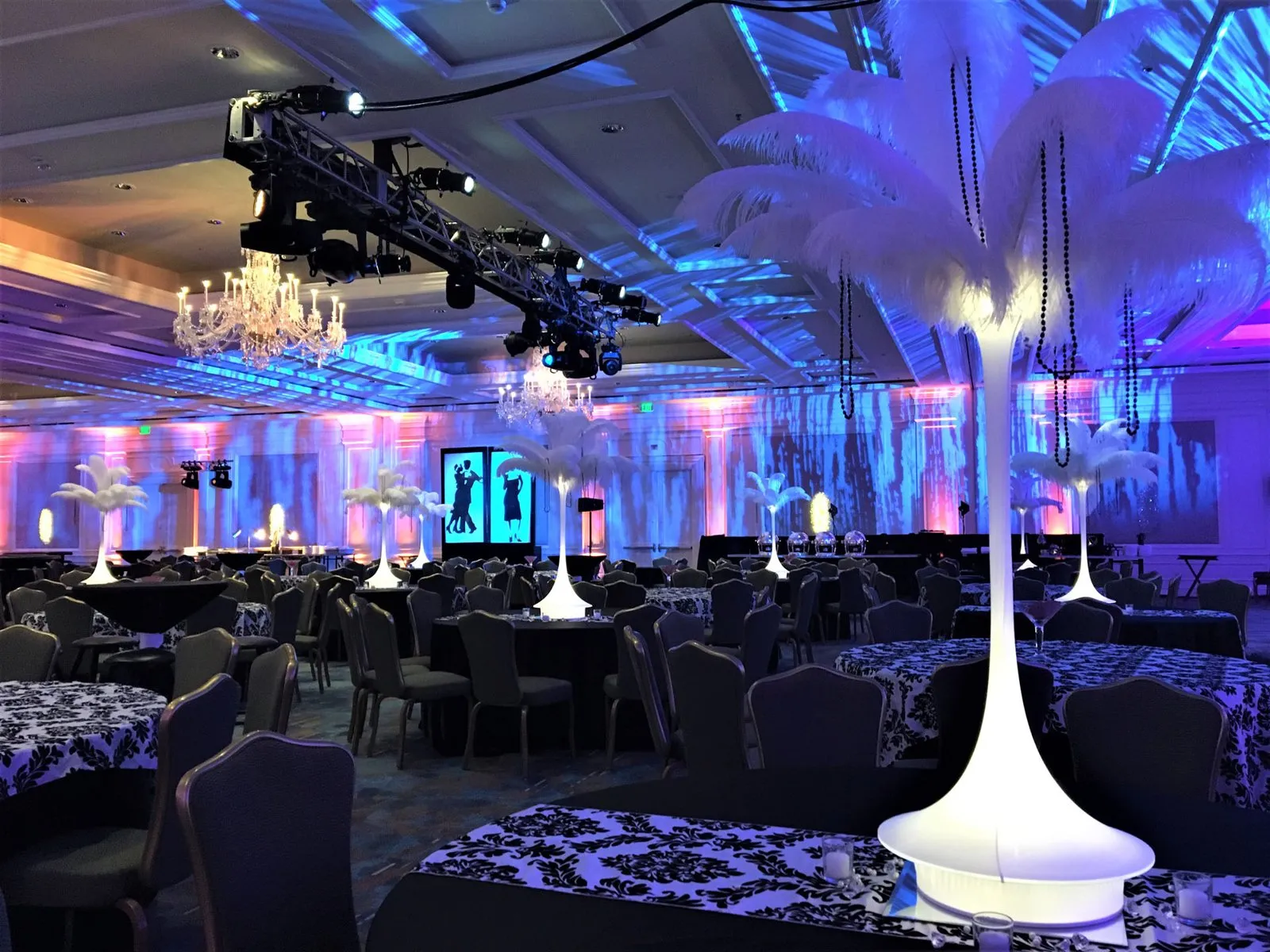 Ballroom styled with purple lighting, lounge furniture and tall white centerpieces