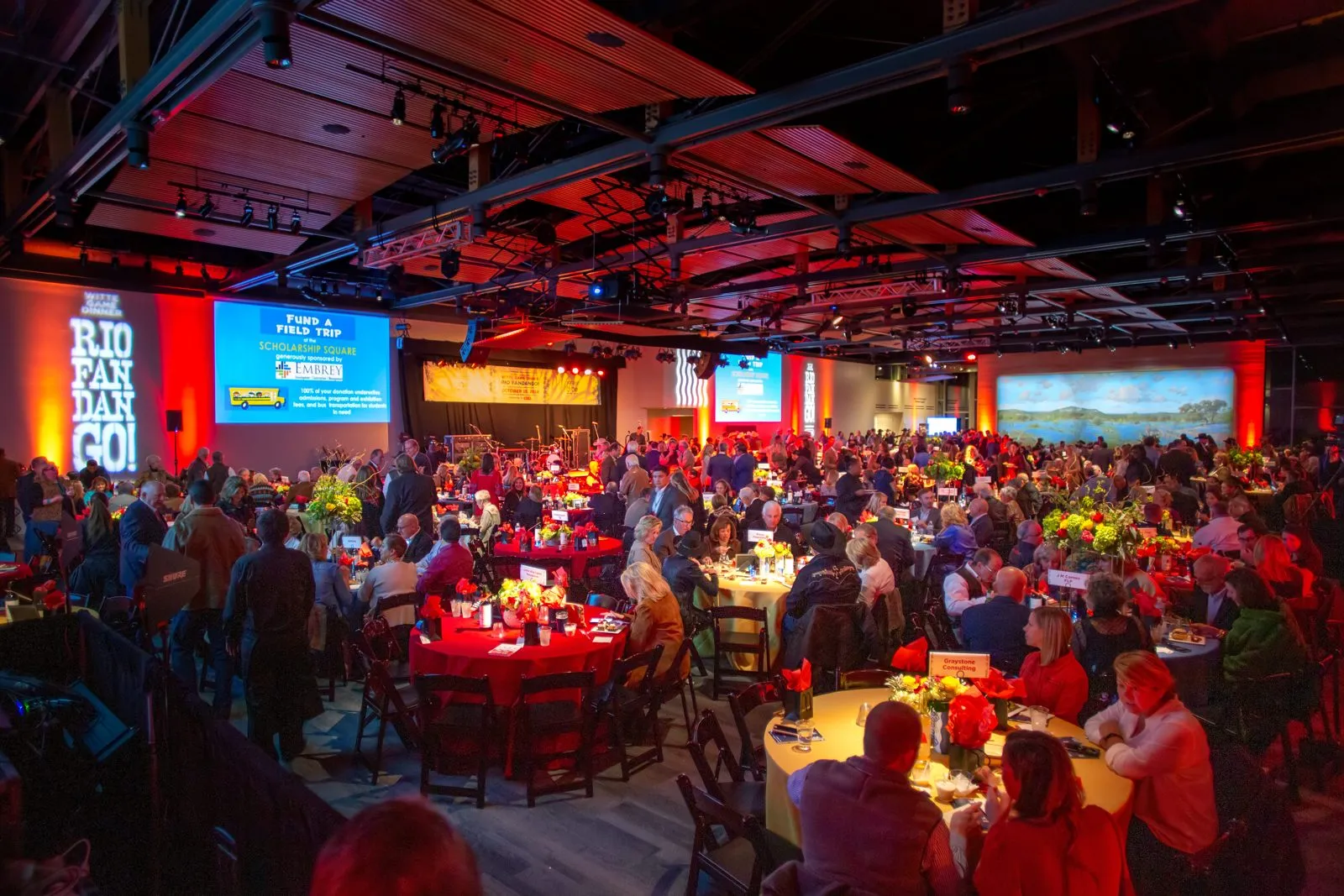 Large ballroom with round tables and red lighting at a company gathering