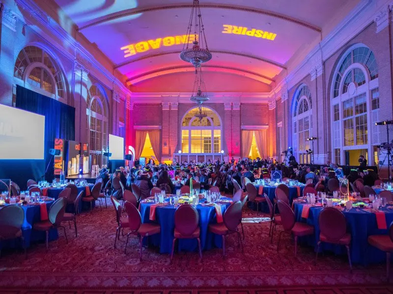 Round tables in a grand hall with pink and blue lighting