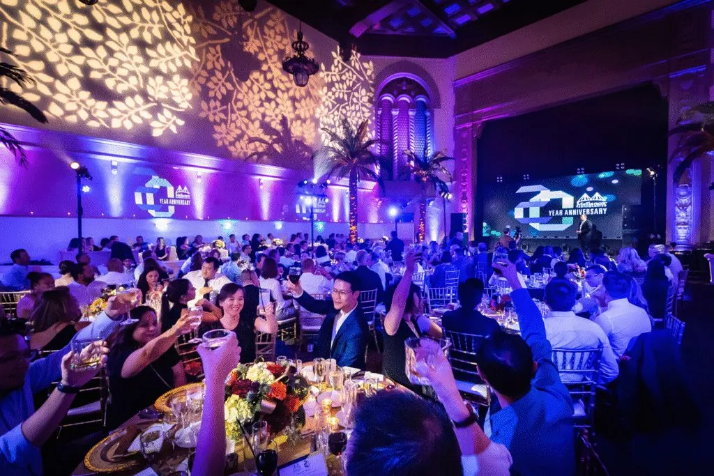 Ballroom with purple lighting and decor above round tables full of guests