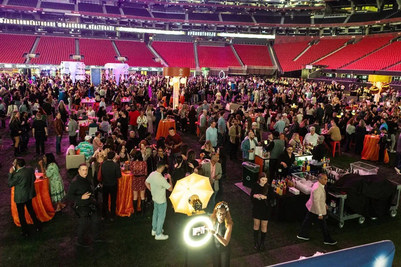 Large company gathering with round tables inside a stadium