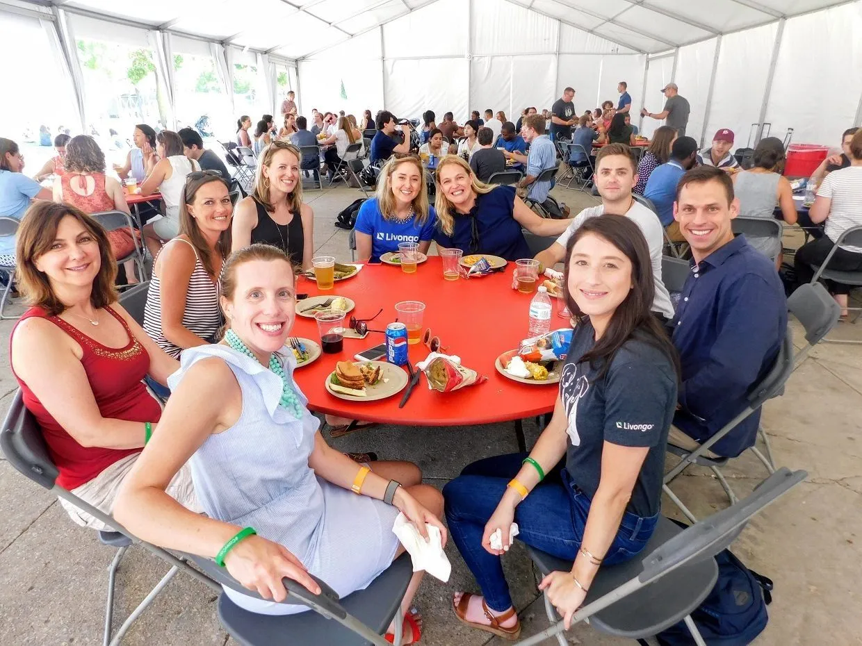 Team members seated at red round tables during a company picnic