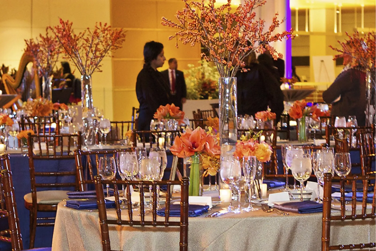 Dinner tables with tall orange floral centerpieces