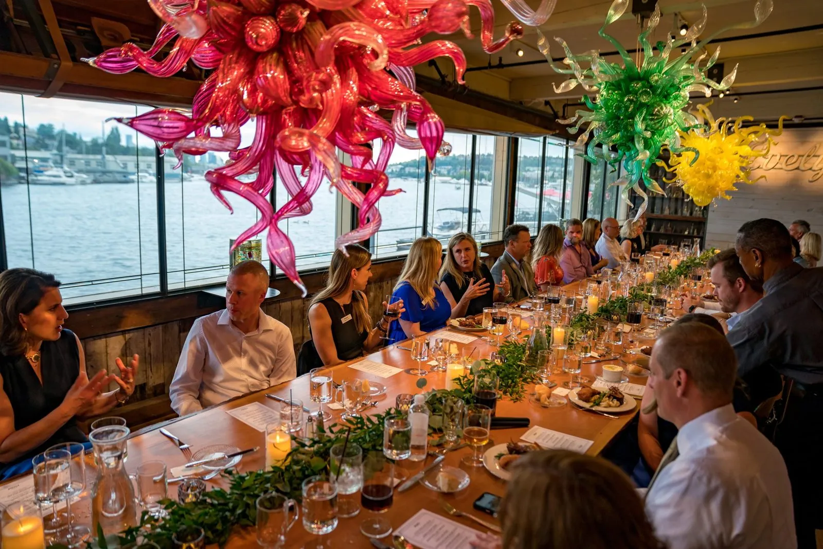 Long dinner table beside a window with colorful glass sculptures at an incentive program