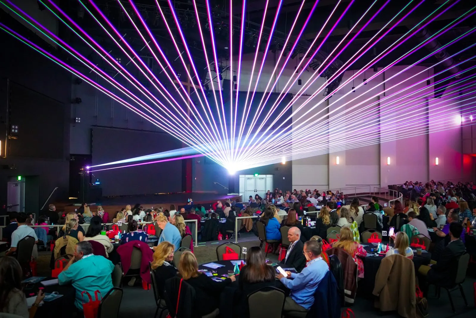 Large seated audience at an event with laser lighting
